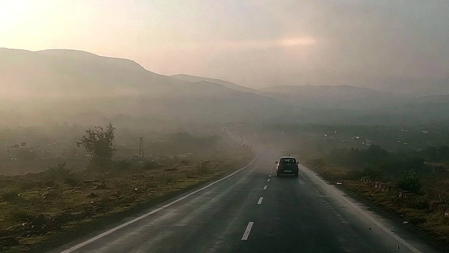 Front dashcam view of a car on a misty mountain road